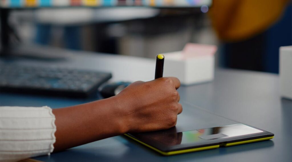 photo of a woman's hand using a tablet and designing a social post