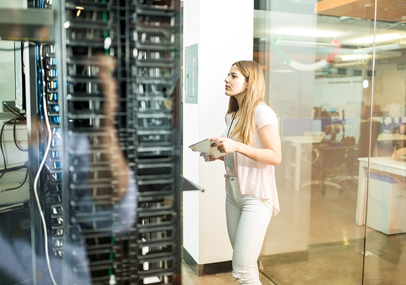 woman standing in the data centre and looking at the server racks